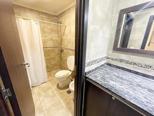 y baño con aseo y ducha con espejo. en Miralejos 9 Apartamentos en Villa Carlos Paz