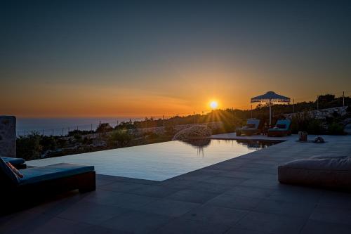 a swimming pool with a sunset in the background at Terra Lucis Mountain Residences in Agios Leon