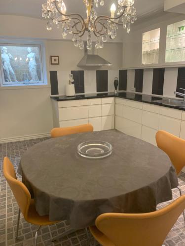 a kitchen with a table with chairs and a chandelier at Skovbakkegaardens Bed & Bath - Værelser med eget bad in Aalborg