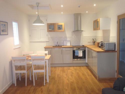 a kitchen with white cabinets and a table and chairs at The Gallery Two Bedroom Apartment in Oakham