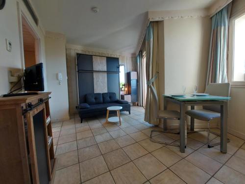 a living room with a blue couch and a table at Studio les Pieds dans L'eau au bord du lac d'Annecy in Duingt