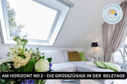 a living room with a white couch and flowers at Am Horizont No 2 Fewo für 4 Pers, 2 Schlafzimmer, Südbalkon, W-LAN, Homeoffice geeignet, Parkplatz in Zingst