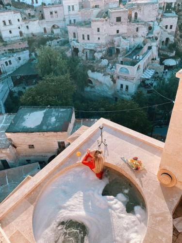 a woman sitting in a bath tub on top of a building at Cappadocia Gamirasu Cave Hotel in Urgup