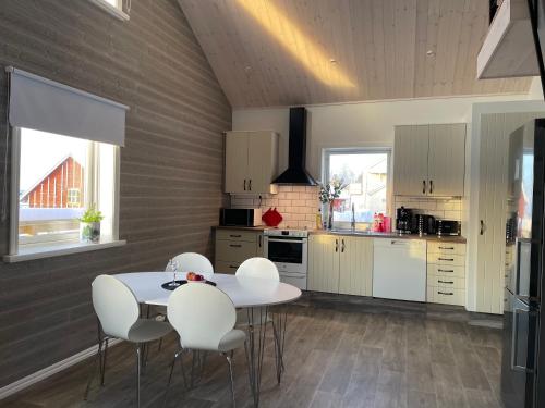 a kitchen with a white table and white chairs at Underbar Timmerstuga i Centrala Oviken in Oviken
