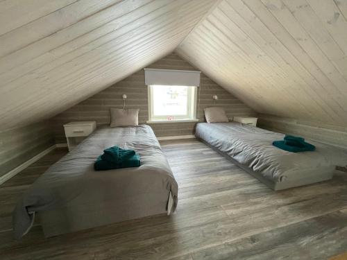 2 bedden in een zolderslaapkamer met houten plafonds bij Timmerstuga i Centrala Oviken in Oviken