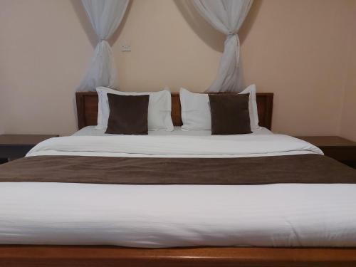 a bedroom with a large bed with white sheets and pillows at Roza Guest House in Naivasha