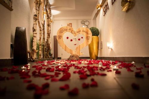 Un mucchio di rose rosse sul pavimento di fronte a un cuore di Chalet VitaSpa - Whirlpool & Sauna PrivatSpa a Pegnitz