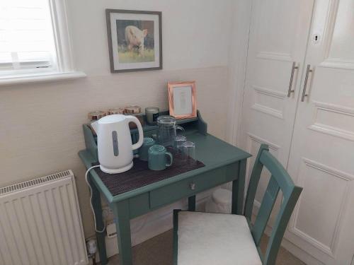 a small green table with a tea kettle on it at JESMOND House B&B room 1 in Hull