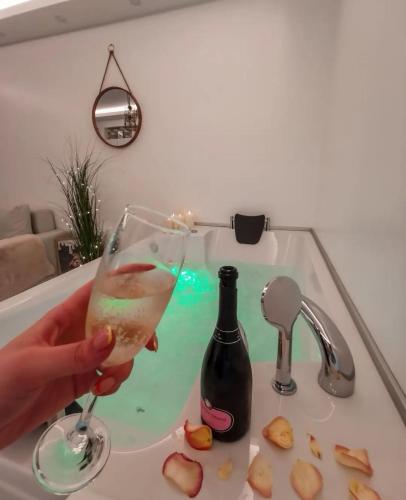 a person holding a glass of wine in a sink at Teddy Bear Jacuzzi Spa Apartment Sarajevo in Sarajevo