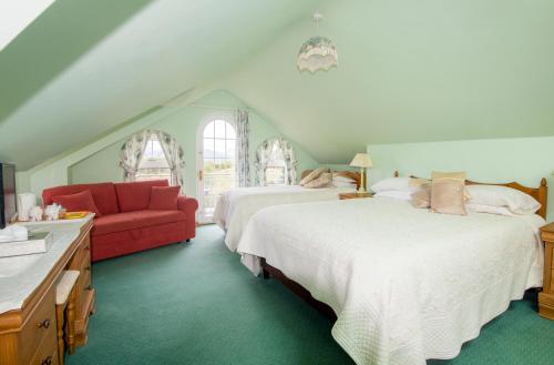 1 dormitorio con 2 camas y sofá rojo en Oakfield en Kenmare