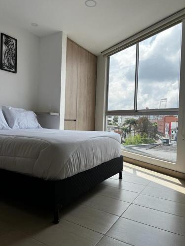 a bedroom with a bed and a large window at Apartamento de lujo Manizales in Manizales