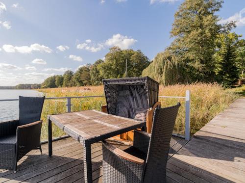 a wooden table and chairs on a deck next to the water at Wandlitzsee in Wandlitz