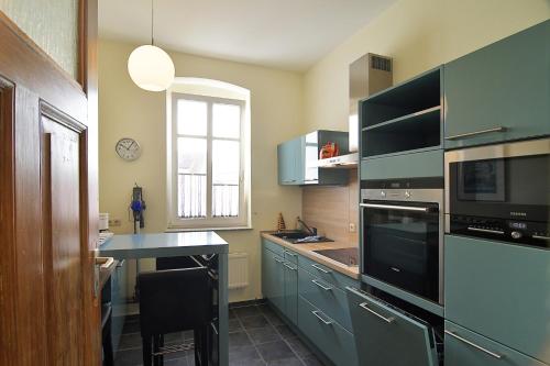 eine Küche mit blauen Schränken, einem Tisch und einem Fenster in der Unterkunft Hamburg App. 01 in Ahlbeck