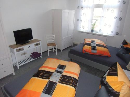 Cet appartement comprend une chambre avec 2 lits, une télévision et un canapé-lit. dans l'établissement Udos Gästewohnung, à Cottbus