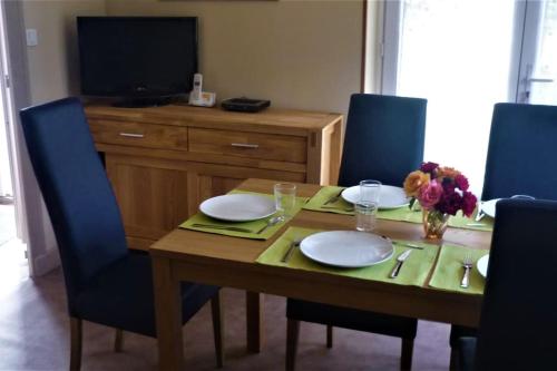 una mesa de comedor con platos y flores. en Calme et sérénité au gîte des hortensias, en Vaux-en Couhé