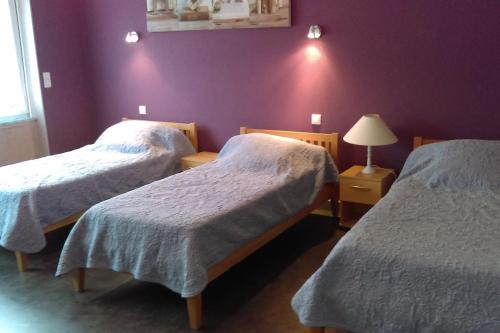 2 łóżka w pokoju z fioletową ścianą w obiekcie Calme et sérénité au gîte des hortensias w mieście Vaux-en Couhé