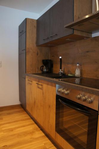 a kitchen with wooden cabinets and a stove top oven at Apart Egger in Schwendau