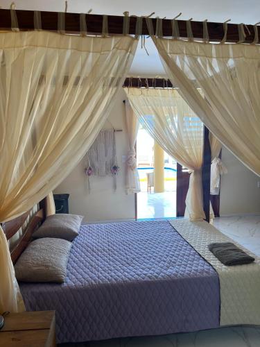 a bedroom with a bed with drapes at Casa Ferreira Cumbuco in Caucaia