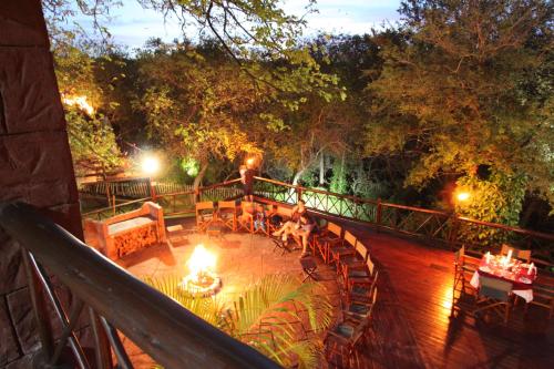 a deck with a table and chairs and lights on it at Grand Kruger Lodge and Spa in Marloth Park