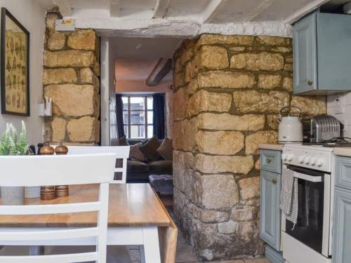 - une cuisine avec un mur en pierre et une cuisinière dans l'établissement Inglenook Cottage, The Cotswolds, à Winchcombe