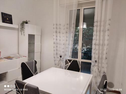a white table and chairs in a room with a window at Casailaekobe in Bologna