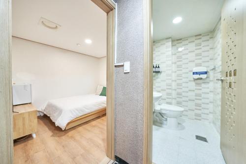 a bathroom with a toilet and a bed in a room at K'STAY Sinchon in Seoul