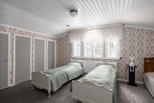 een slaapkamer met 2 bedden en een raam bij Maalaishuvila Wanha Virkailija Iittala in Hämeenlinna