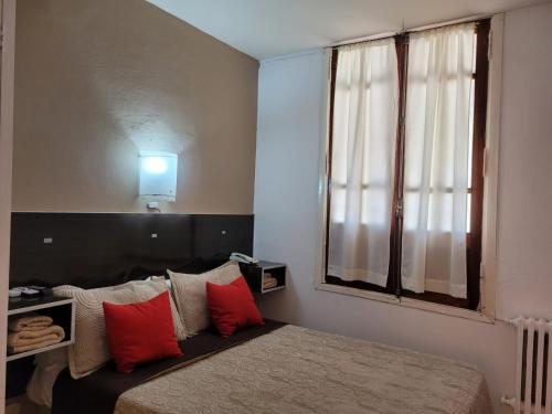 a bedroom with a bed with red pillows and a window at Cerro Uritorco Hotel in Capilla del Monte