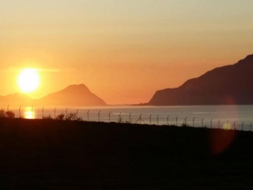 a sunset over the water with mountains in the background at Nyoppusset leilighet. Dusj med steambad. in Åheim
