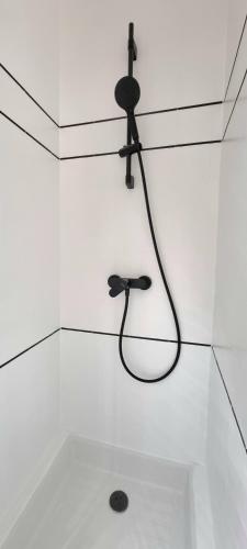 - une douche dans une chambre blanche avec un tuyau noir dans l'établissement Sur un nuage - Terrasse - Gare - Hypercentre, à Toulouse