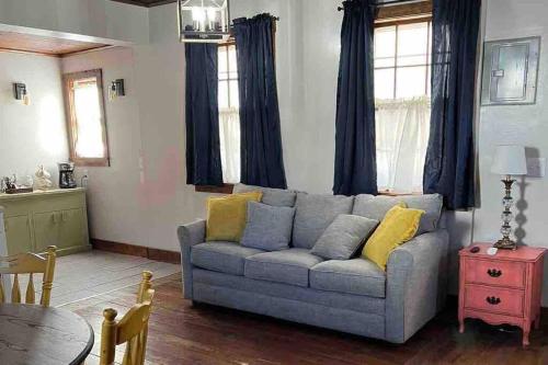 a living room with a gray couch with yellow pillows at Hanna’s Cottage-Downtown Hermann in Hermann