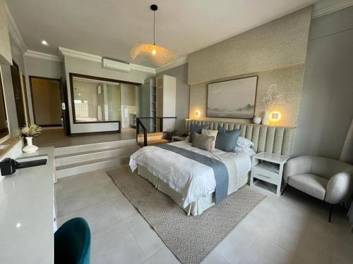 een slaapkamer met een bed, een stoel en een bank bij Coco De Mer Boutique Hotel in Ballito