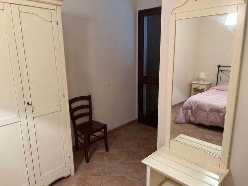 a mirror in a bedroom with a bed and a chair at Case Vacanza Santoro in Custonaci