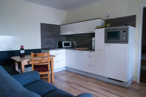 a kitchen with white cabinets and a table and a microwave at Gästehaus Zur Langen Lacke in Apetlon