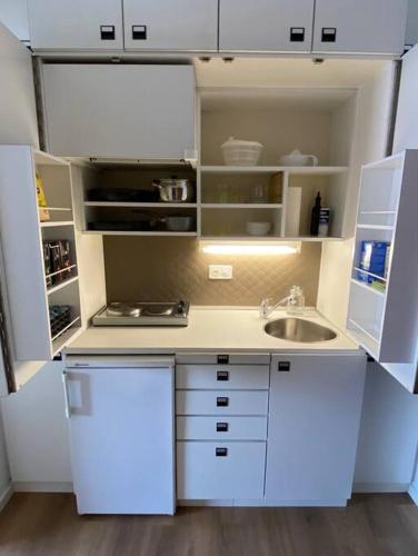 a small kitchen with white cabinets and a sink at Alloggio con favolosa vista lago Lugano Paradiso in Paradiso