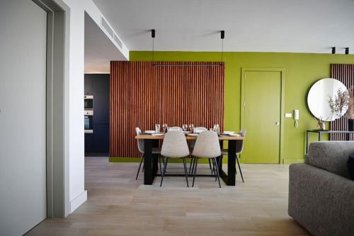 uma sala de jantar com uma mesa com cadeiras e uma parede verde em Cliff Edge Apartment in Xaghra em Taʼ Bullara