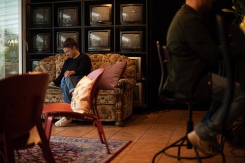 a man sitting on a couch in a living room at DAS SCHÖNE LEBEN Pop-Up Hotel in Hornberg