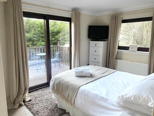 a bedroom with a bed and a balcony with a television at Stunning 4-bedroom Cabin with Hot Tub in Beattock! in Beattock
