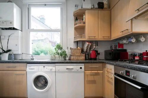 a kitchen with a washing machine and a window at Stylish room with private bath & terrace in super central Clapham Junction minutes from Victoria, Waterloo in London