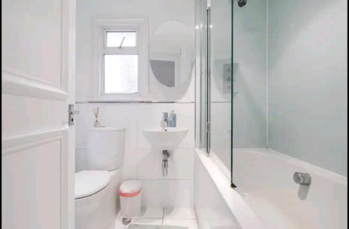 Baño blanco con aseo y lavamanos en Stylish room with private bath and terrace in centrally located Clapham en Londres
