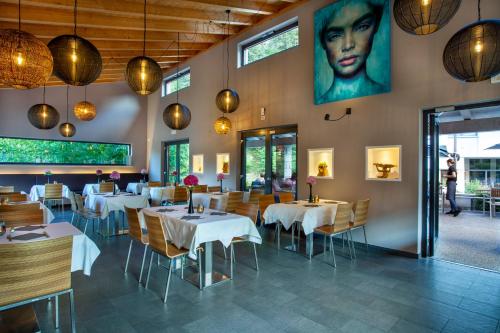 クロネにあるSportcamping & Glamping Resort Rio Vantoneのテーブルと椅子が置かれたレストランと壁に飾られた女性