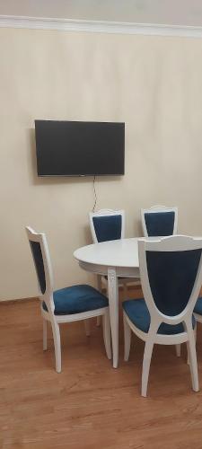 a white table and chairs with a tv on a wall at D&G guest house in Yeghegnadzor