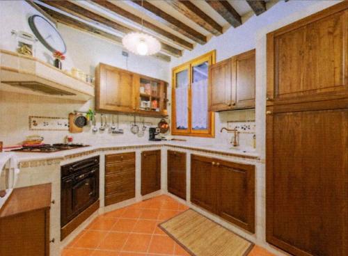 a kitchen with wooden cabinets and an orange tile floor at Rifugio alle Vele in Venice