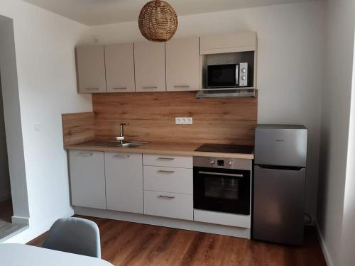 a kitchen with white cabinets and a sink and a refrigerator at Au Bocage Parfumé Gîte La Cigaline in Wirwignes