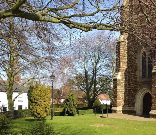 a brick building with trees and a grass yard at B&B Harlington Manor in Harlington