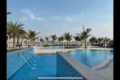 a swimming pool with palm trees in a resort at Balqis Residense Palm Jumeirah,Pool, Beach, Top floor, Full sea view, Restaurants in Dubai