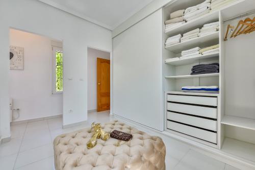 een witte kleedkamer met een getufte kruk en een kast bij Very Luxurious Seaside Villa With Private Pool in El Campello
