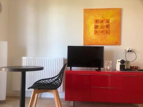 - une commode rouge avec une télévision en haut dans l'établissement charmant appartement en plein coeur de Trouville, à Trouville-sur-Mer