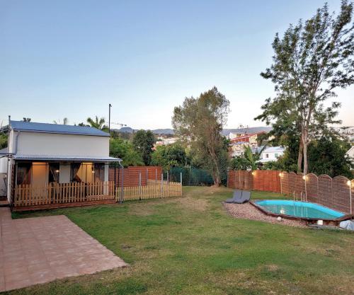 un patio trasero con una valla y una piscina en Tiny House Chaleureuse au Style Contemporain Minimaliste en Le Tampon