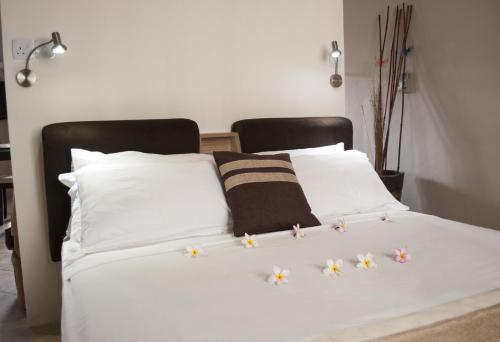 a white bed with white pillows and flowers on it at Lharmonie Villa in Pereybere